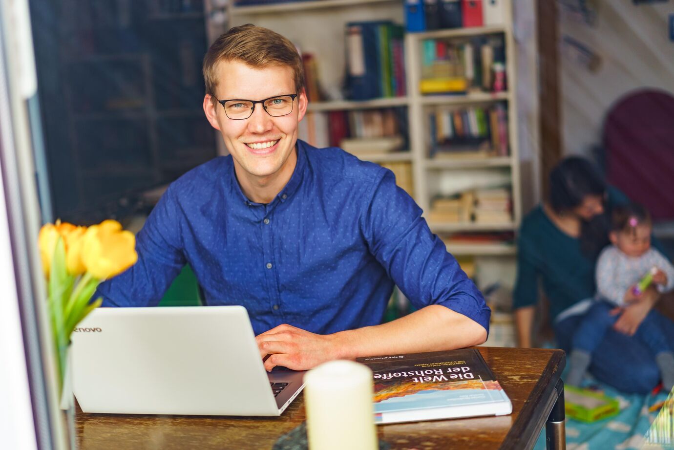 Teilzeitstudium an der THGA Teilzeitstudium an der THGA. Ein Studierender sitzt am Laptop und blickt in die Kamera. Im Hintergrund sind eine Frau und ein kleines Kind zu sehen.