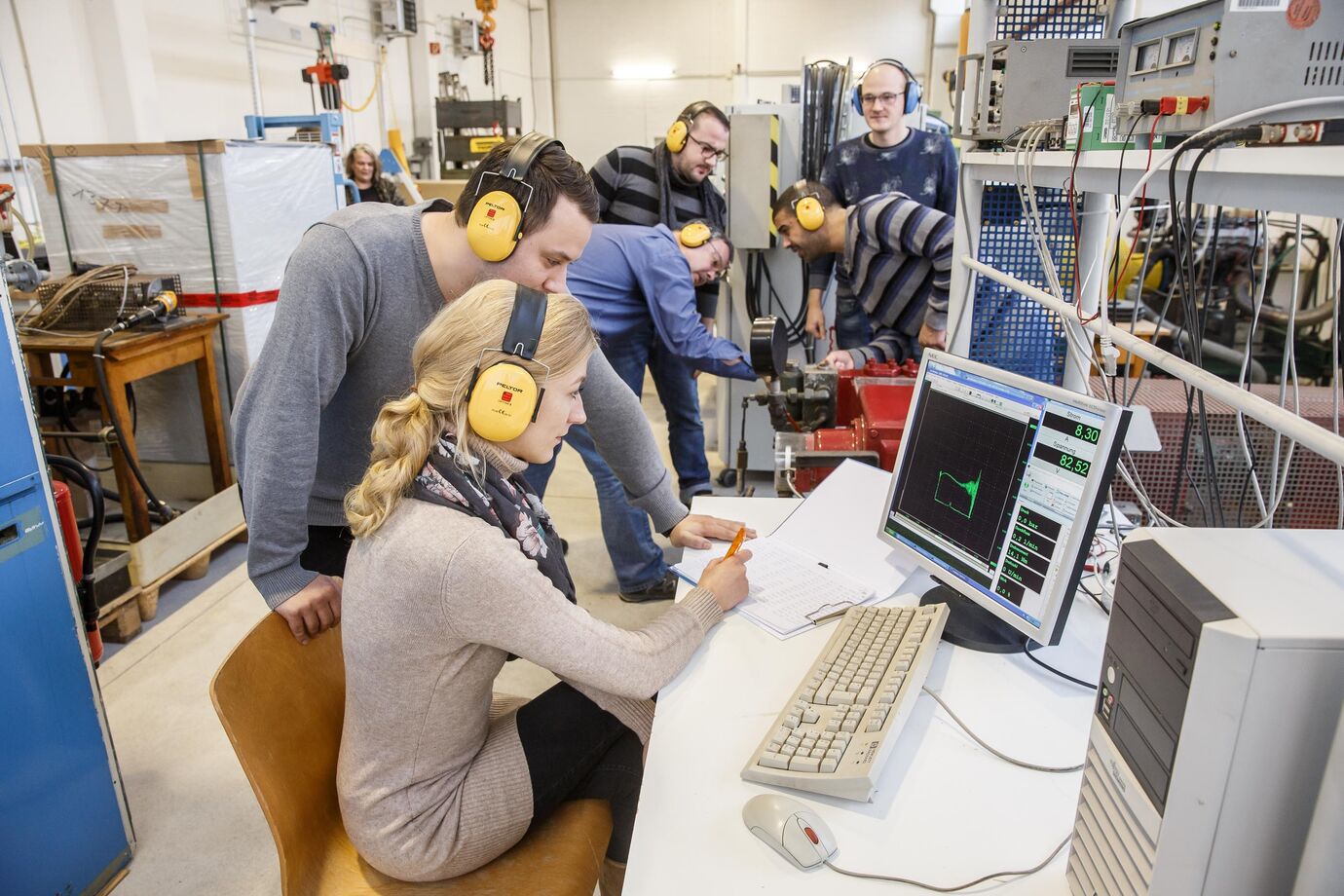 Praktikum im Labor mit Testing. Studierende mit Hörschutz machen entsprechend praktische Versuche.